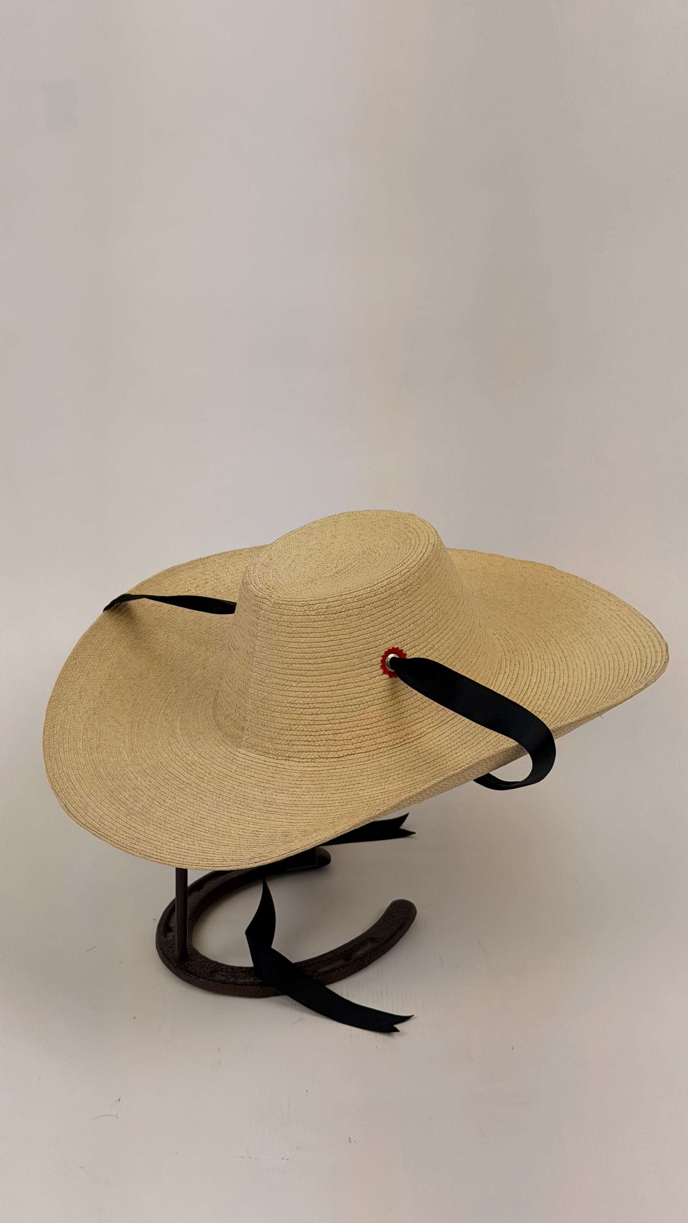 Beige straw hat with black ribbon on a white background