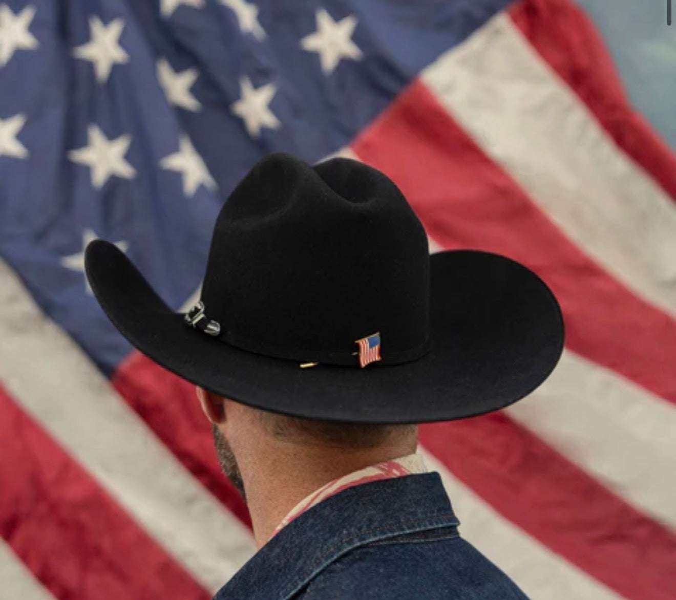 Person wearing a black cowboy hat with an American flag emblem