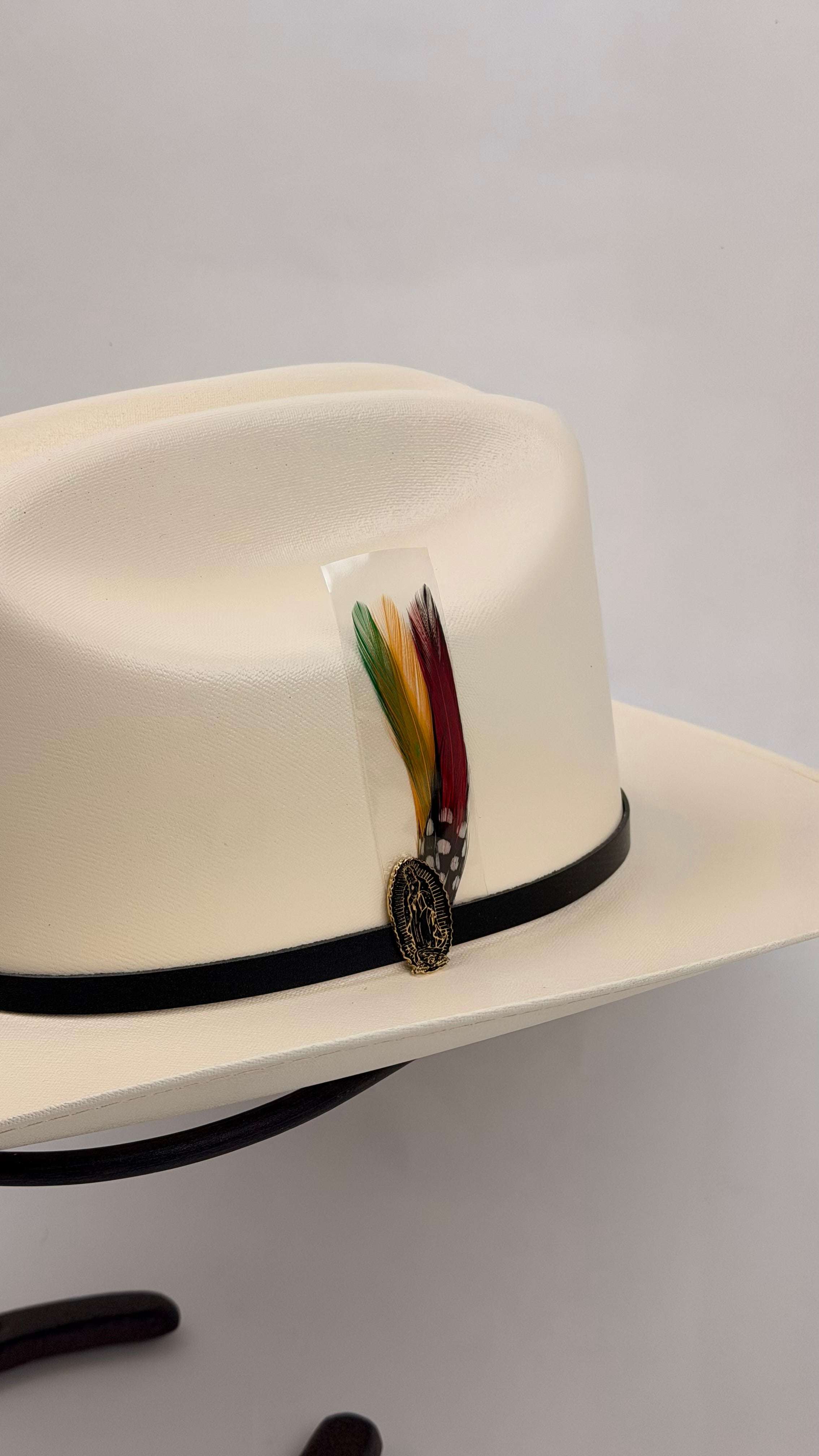 White cowboy hat with a black band and colorful feather 