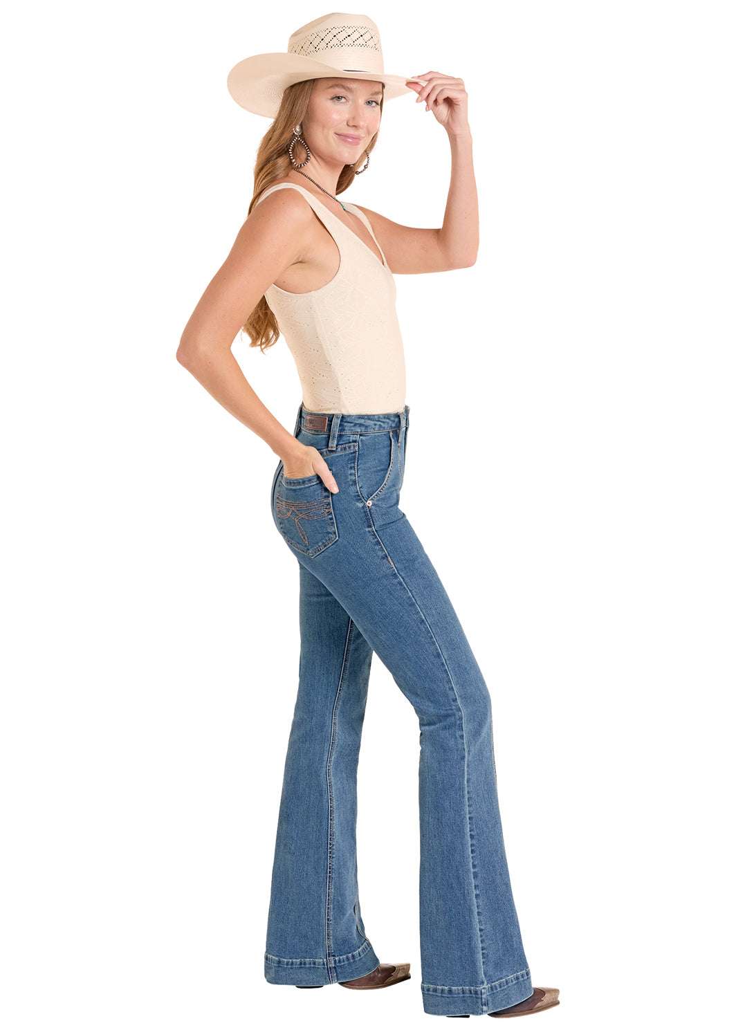 Woman wearing a beige top and blue jeans with a cowboy hat 
