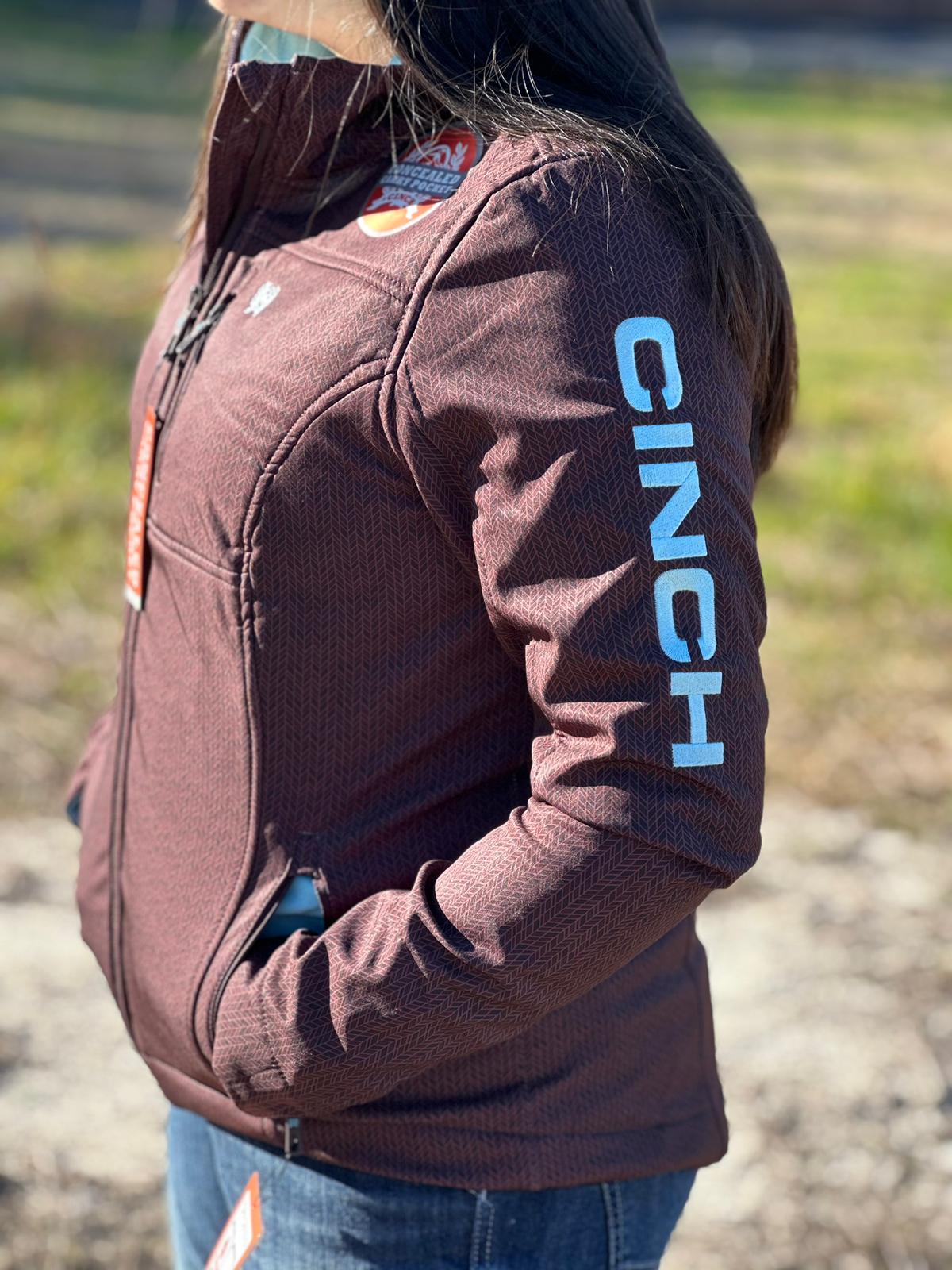 Cinch Softshell marrón para mujer con logotipo azul en la manga y cremallera completa, bolsillo de transporte oculto